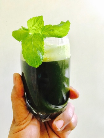 A glass of peppermint juice in the handの素材
