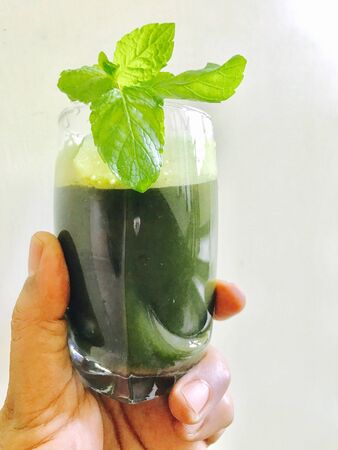 A glass of peppermint juice in the handの素材