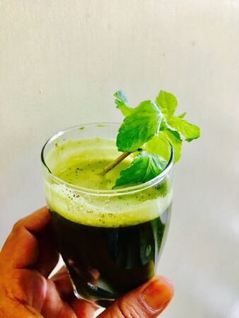 A glass of peppermint juice in the handの素材