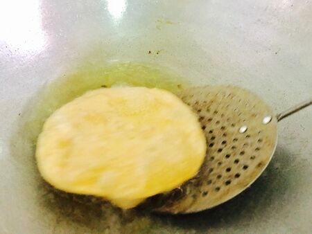 Oily breads are cooking in a frying pan in the kitchenの素材