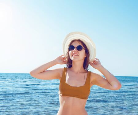 Beautiful girl in bikini, glasses and hat in clear sea waterの写真素材