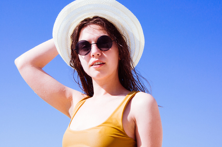 Beautiful girl in sunglasses and hat against the seaの写真素材