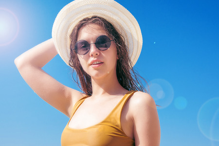 Beautiful girl in sunglasses and hat against the seaの写真素材