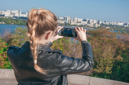 A beautiful blonde girl making photos of the city on a smartphoneの写真素材