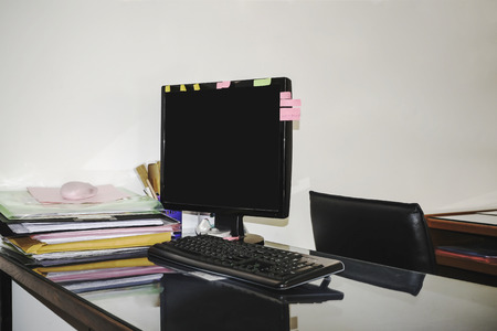 Modern personal computer and Pile of unfinished documentson desktop in office roomの写真素材