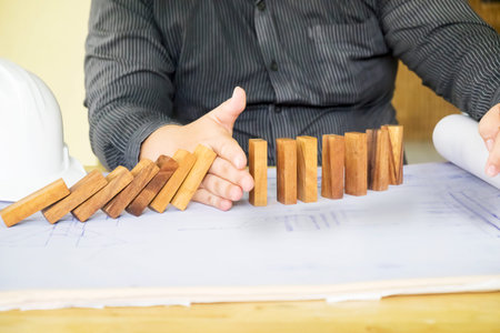 Close up of businessman hand stop dominoes continuous toppled vintage tone.
