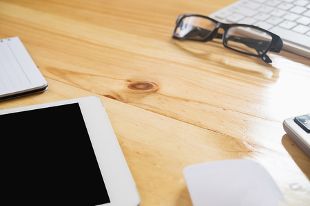 Office desk table with computer, supplies, tablet, calculator, pen and glasses . Top view with copy space (selective focus)の写真素材