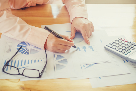 Asian Business woman hand pointing at business document during discussion at meeting and  using a calculator to calculate the numbers.Vintage toneの写真素材