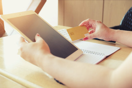 Woman's hands holding credit card and using laptop. Online shopping vintage tone