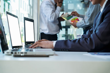 business man using laptop computer on office table with two partners interacting on background
