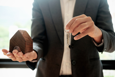 real estate agent holding house key to his client after signing contract,concept for real estate, moving home or renting propertyの写真素材