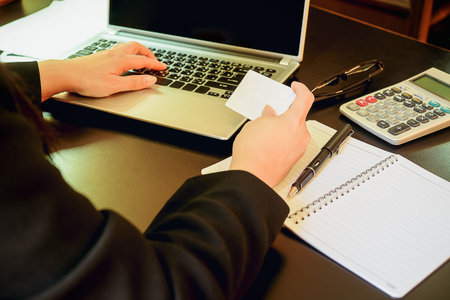 Woman's hands holding a credit card and using smart phone for online shopping.vintage tone