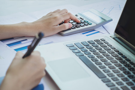 Asian Business woman using a calculator to calculate the numbers