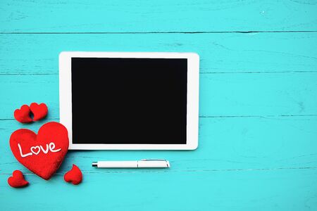 Red heart and White digital tablet on blackwooden tableの写真素材