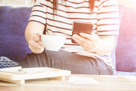 woman hand holding using smartphone in coffee shop, vintage tone, selective focus