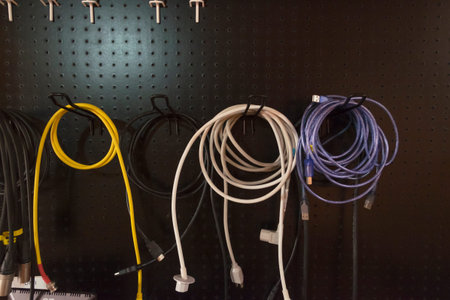 Colorful of electric wire hanging on storage rack on black background. Storage of cables on the wall...