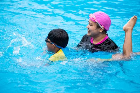 mother teach her boy for smiw in poolの写真素材