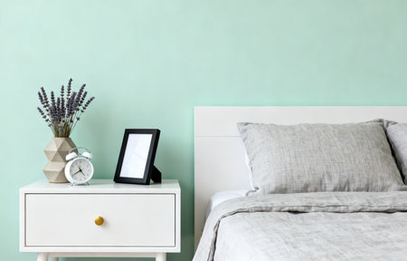 Modern bedroom interior with bedside table, alarm clock and bouquet of lavenderの素材
