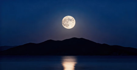 Full moon over the sea at night with mountains and hills in the backgroundの素材