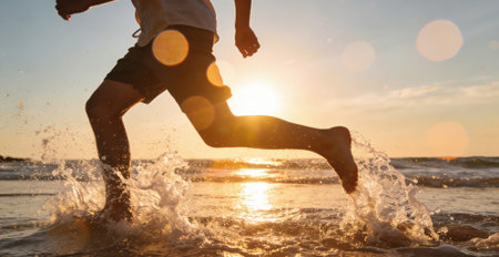 Silhouette of a boy running on the beach at sunset.の素材