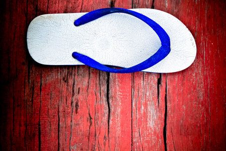 A casual one side slipper on wood red floor