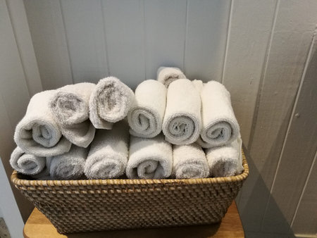 pile of cloth, hand towel, table napkin, handkerchief on the basket with blur white wooden wall backgroundの写真素材