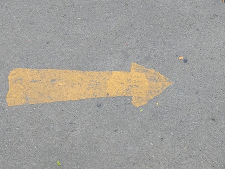 Road surface with yellow arrow sign, outdoor symbol, going forward, left to right, abstract photoの写真素材