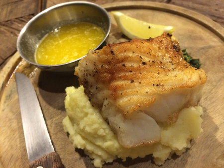 Pan fried salmon fish on mash potato with butter sauce seasoning with herb and pepper with lemon...
