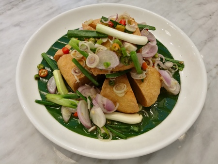 Deep fried egg tofu Thai salad with chilli garlic pepper and onion on banana leaves,Vegetarian menu,Veggie dish,Yum Thai salad,Top view closeup Focus-on-foreground with blur marble table backgroundの写真素材