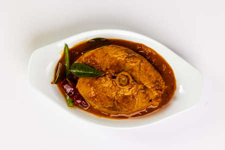 Spicy Fish Curry. Traditional Indian Kerala special fish curry arranged on a white bowl garnished with curry leaves on white background. Top Viewの写真素材