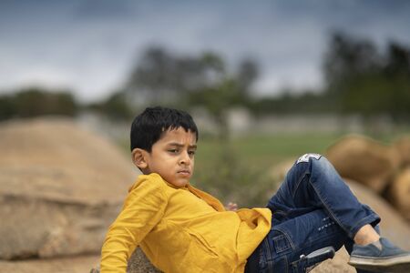 Pretty, Cute Little boy In Yellow Shirt, Blue jeans watching sunset under stormy sky backgroundの写真素材