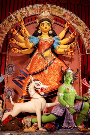 Goddess Durga idol at decorated Durga Puja pandal, shot at colored light, at Kolkata, West Bengal,...