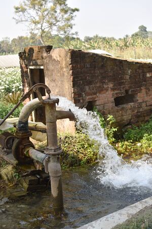 water supply shallow machine water pump supply farm land green flow grassの写真素材