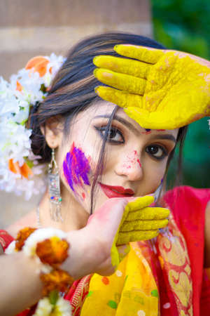 Pretty young indian girl showing colourful palm and celebrating Holi with colour splash, popular hindu festival celebrated across India.の写真素材