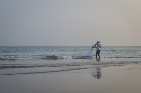 A fisherman with fishing net, the traditional way of fishing of a small village in coast of Indian. The Subject of the image is exciting, sensational and calm. This photography is taken in as landscape style may be used as a background, wallpaper, screen saver.の写真素材