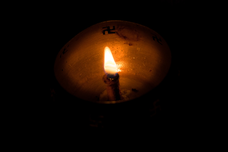 Flame of oil lamp on dark background, a burning oil lamp in darkness, with copy space. concept of removing darkness with a flame, are common in india and nepal for festival usage.の写真素材