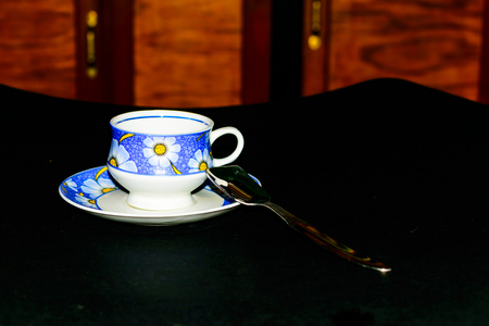 Single coffee cup on the plate with spoon in dark backgroundの写真素材