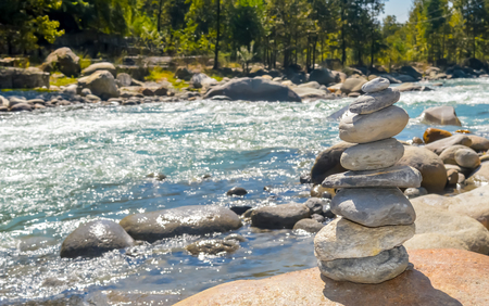 Balance and wellness retro spa concept, inspiration, zen-like and wellbeing tranquil composition. Close-up of white pebbles stack balanced stones on the rocky shore over near river side.の写真素材