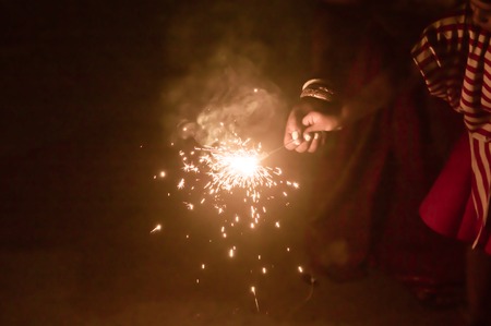 Sparklers on hand on black background on a low light evening. Selective focus on sparklers. Mother, Daughter, Woman, Lady, girl, kid, child holding sparkles.の写真素材