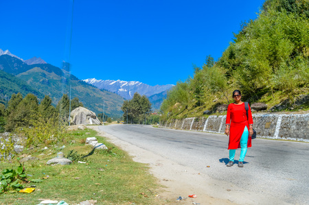 A lady in red drees standing on a highway. Beautiful landscape panorama view Himalayan valley ofの写真素材