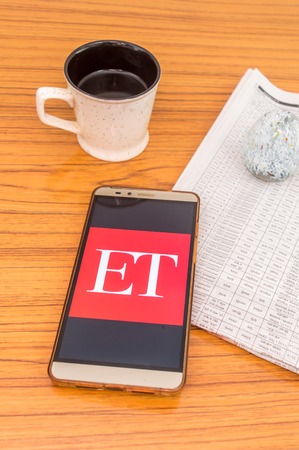 Kolkata, India, February 3, 2019: Economic Times (ET) news app visible on mobile phone screen beautifully placed over a wooden table with a newspaper and a cup of coffee. A Technology Product Shoot.のeditorial素材