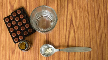View of antioxidants vitamin tablet, pill blisters, a bottle of drug, capsule in measuring spoon, with glass of water placed on the table. Medical Pharmacy theme. High angel, Close up with copy space.の写真素材