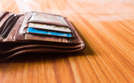 Debit or credit cards in a leather wallet nicely placed at wooden table, studio shot with copy space...