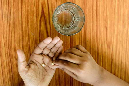 Self-treatment at home as per prescribed by doctor. A teenager boy pouring medicine into her hand....