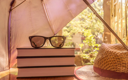 Defending light beams with umbrella. Umbrella protecting beautiful woman things. Books sunglasses...