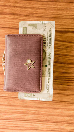 Indian five hundred (500) rupee cash note in brown color wallet leather purse on a wooden table....