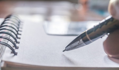 Close shot of a pen writing something on application form paper filling document - signing a contract on foreground. A business credit card on shallow depth of field. Shopping online payment concept.の写真素材