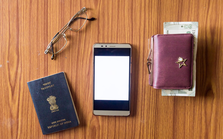 Business still life concept. Personal accessories on table desk. Indian passport, money purse, paper currency, eye glasses and mobile phone with blank screen. Top view with copy space for text. Mockupの写真素材