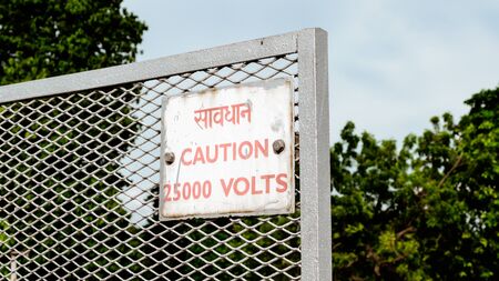 Caution 25000 high voltage safety warning sign in a clear and straight instructions to communicate at work with everyone for spreading awareness about a potential risk in workplace around the premises. Written in Hindi and English language.の写真素材