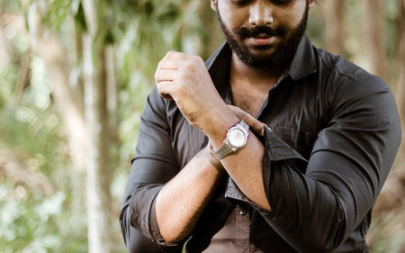 Portrait of Cropped Well-dressed man wearing wristwatch and rolling up shirt sleeves. Front View....